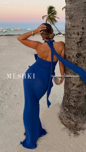 This ad showcases a woman wearing a blue Meshki dress on the beach with a focus on wedding wear.