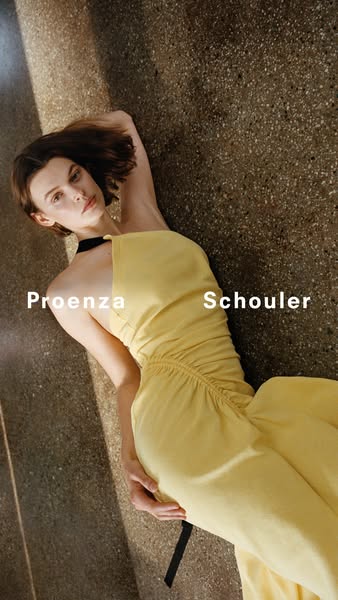 This ad features a woman lying on a speckled surface wearing a yellow dress with a black neckline and waist tie. The bra
