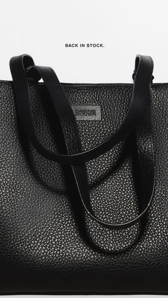 This image ad showcases a close-up view of a black tote bag. The ad uses simple text to highlight that the bag is back i