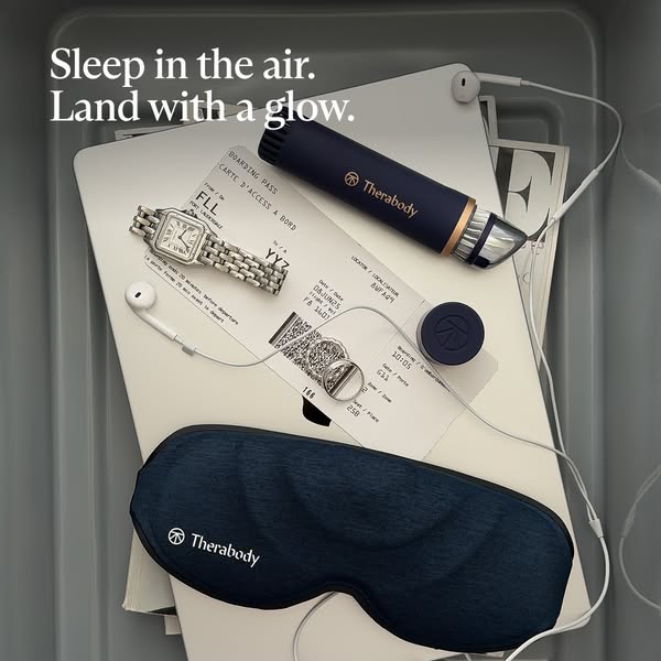 A flatlay of a selection of Therabody products sits on top of a boarding pass in what appears to be an airplane tray. Th