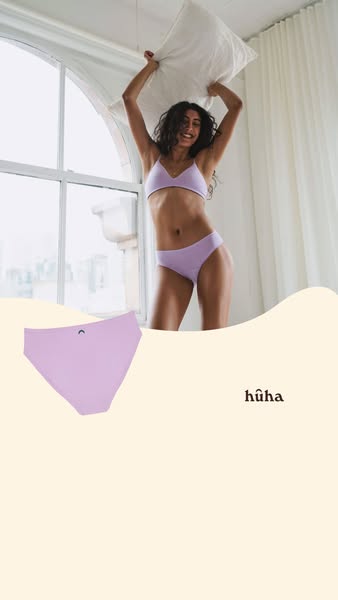 This image ad for hūha intimates features a woman in a matching bra and panty set standing in front of a window with a p