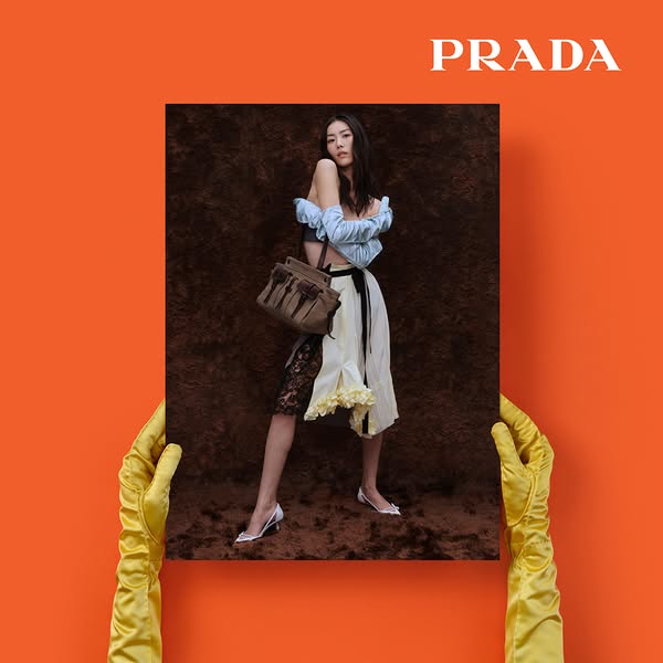 The image is a product shot of a Prada handbag held against an orange background.