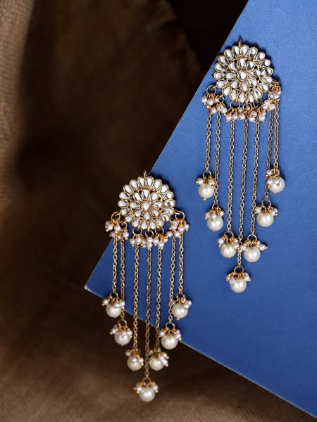 An image ad showcasing ornate gold and pearl earrings displayed on a blue and brown surface.