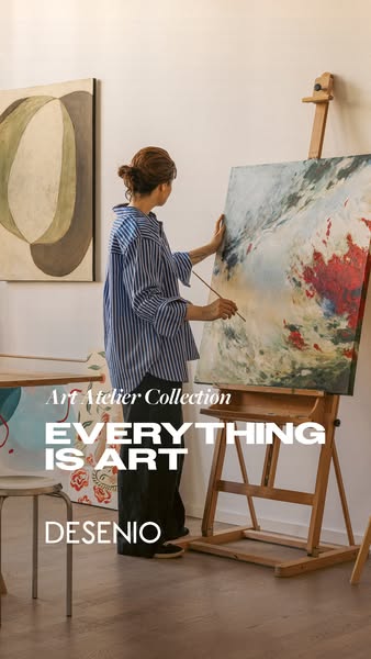This image ad for Desenio's Art Atelier Collection features a woman painting on a canvas in a well-lit studio. The o