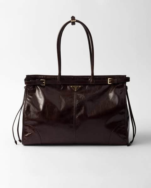 This ad showcases a brown leather Prada handbag against a neutral background.