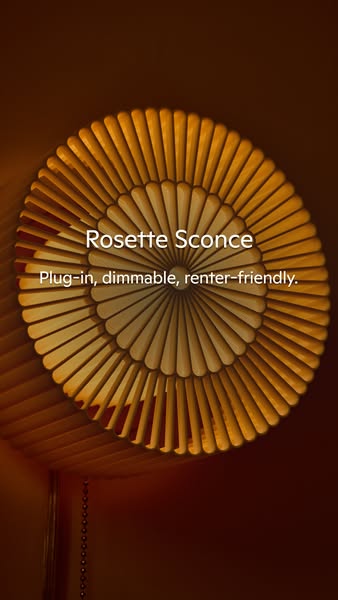 The ad showcases a Rosette Sconce, highlighting its plug-in, dimmable, and renter-friendly features. It is likely intend