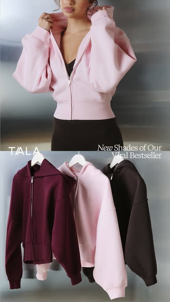An image showcasing a model wearing a pink TALA cropped zip-up hoodie and additional hoodies of the same style in the co