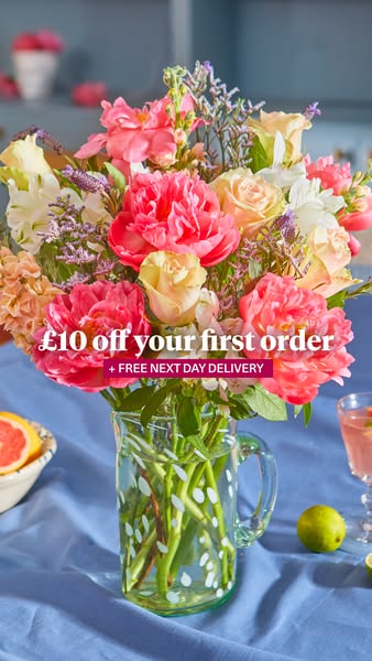 This image ad features a close-up of a colorful flower arrangement in a glass pitcher, promoting an offer of £10 off the