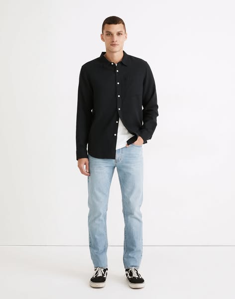 This ad features a man wearing a black button-down shirt, light wash jeans, and black sneakers. The ad is likely for the
