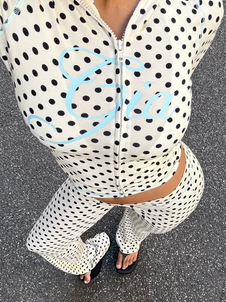 This ad features a person wearing a polka dot tracksuit. The tracksuit has a cursive word on the front. The person is st