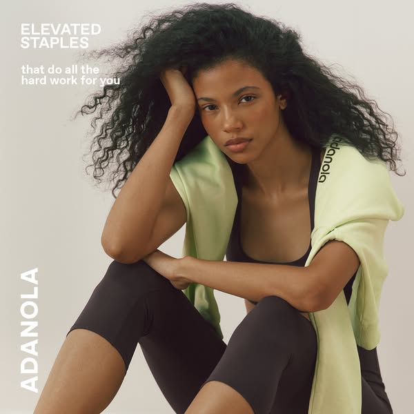 This ad features a woman wearing activewear from the brand ADANOLA. She is also wearing a light green sweater over her s
