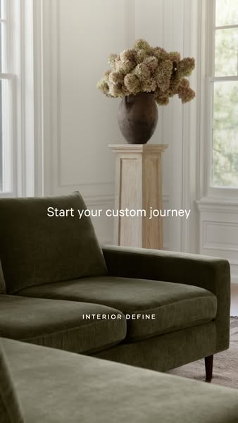 This image ad for Interior Define features a close-up of a green velvet couch in a neutral-toned room. The ad invites vi