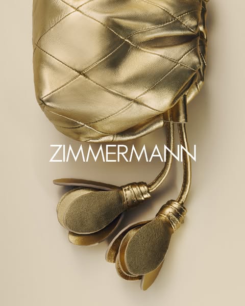 This is an advertisement showcasing a shimmering gold handbag from the brand Zimmermann. The bag's metallic finish, 