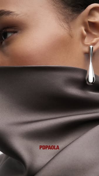 This ad features a close-up of a woman wearing a silver teardrop earring from the brand PDPAOLA. The focus is on the ear