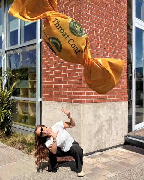 This image ad features a woman in front of a large Throat Coat tea bag, with a playful and energetic pose.