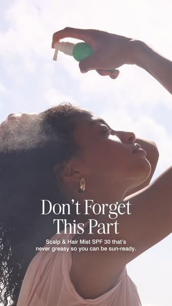 A woman sprays scalp and hair mist into her hair.