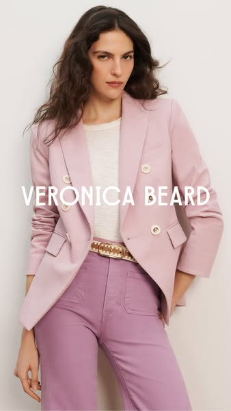 This image ad features a model wearing a light pink blazer and matching pink pants from Veronica Beard. The ad aims to s