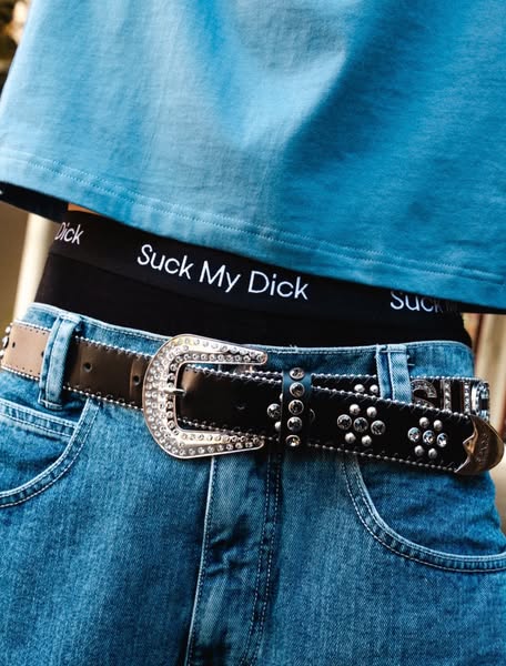 This ad shows a close up shot of a person wearing a bedazzled belt, pants, and underwear with a phrase written across th