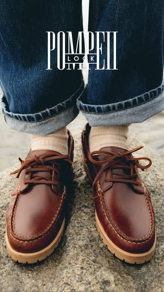 This image ad for Pompeii shoes features a close-up shot of a pair of brown leather boat shoes being worn with rolled je