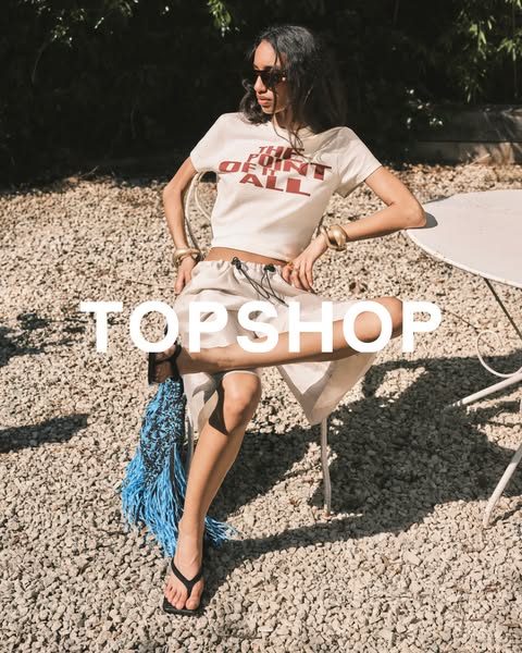 An image ad for Topshop featuring a woman sitting outside wearing clothing from the brand.