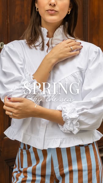 This ad showcases a brand's clothing line by featuring a model in a ruffled white blouse and striped pants, embodyin