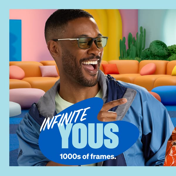 A man wearing glasses is smiling and pointing toward the bottom of the frame, where the brand logo and product offering 