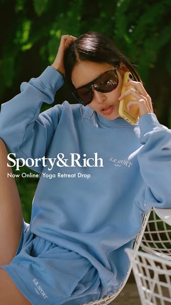 This ad features a woman wearing a light blue shorts and crewneck set from the brand Sporty & Rich. She is sitting o
