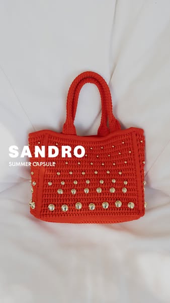 This ad features a bright red crocheted handbag embellished with gold studs. The ad calls attention to the brand and pro