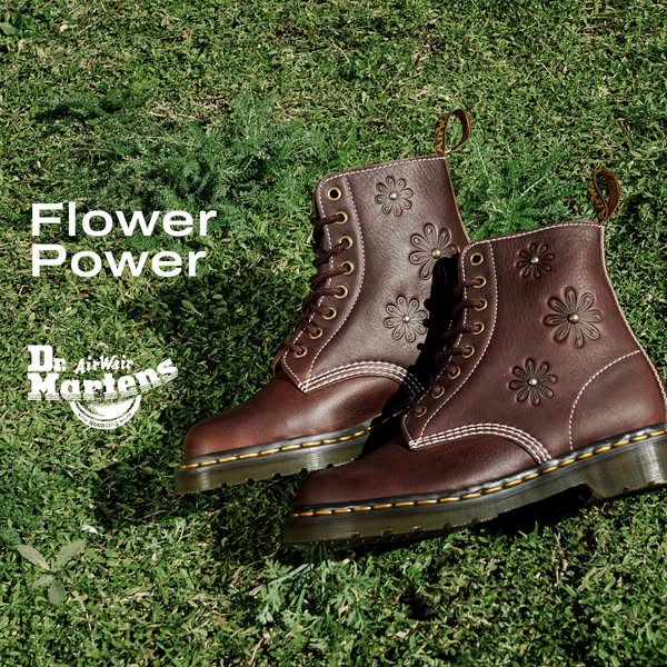 This ad for Dr. Martens features a pair of brown boots with floral designs. The boots are displayed on a grass surface, 
