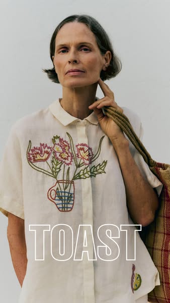 This ad features a model wearing a cream-colored top with an embroidered floral design, showcasing the garment's des