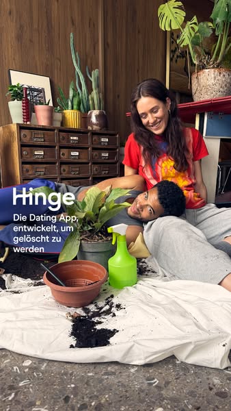 This image ad features a couple tending to plants on the floor of a warmly lit home. The Hinge app is positioned as a to
