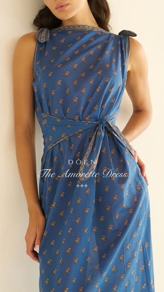 An image promoting the Amorette Dress from DOEN, featuring a model wearing the blue, floral print dress.