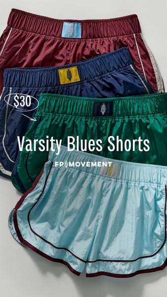 This image ad features a stack of four pairs of FP Movement Varsity Blues shorts in different colors. The shorts are mad