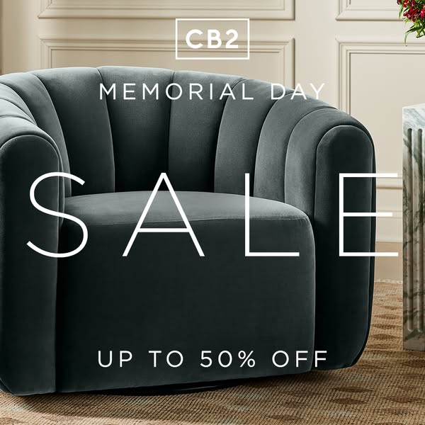 This ad for CB2 promotes a Memorial Day sale with up to 50% off. The image features a gray, rounded armchair against a n