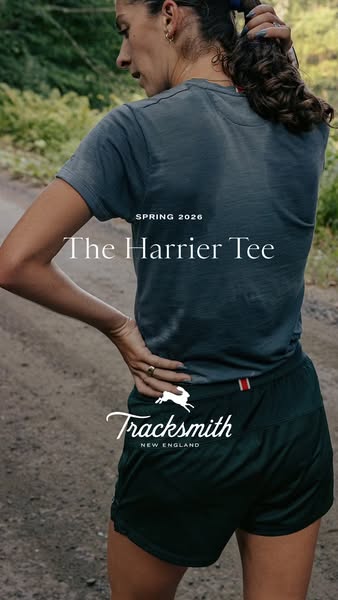 This image ad showcases a woman wearing running apparel by Tracksmith, specifically the Harrier Tee and running shorts. 