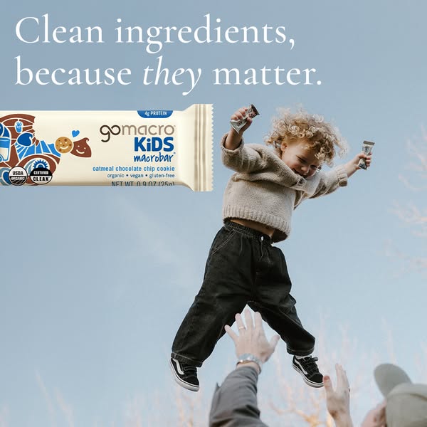 A GoMacro ad showing a young child being tossed into the air as he holds mini GoMacro bars. The ad's headline states