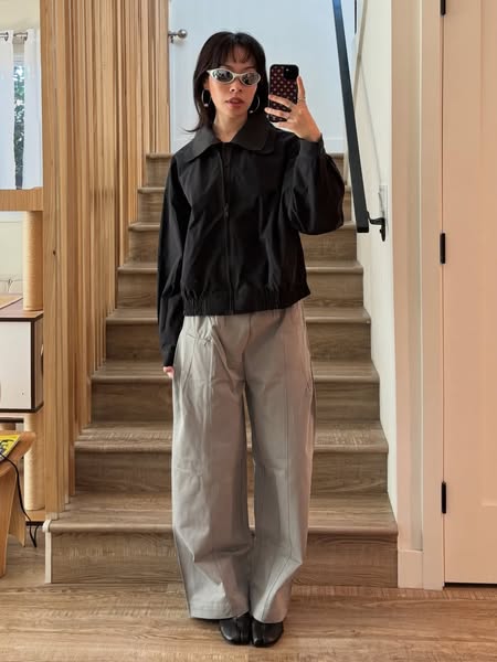 The ad showcases the model wearing a black jacket and gray pants.