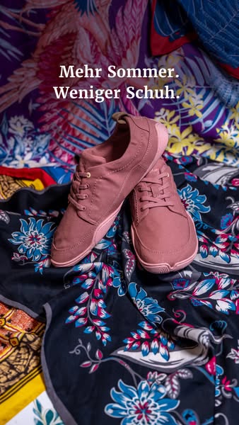 An eye-level shot shows a pair of pink shoes laying on their sides on top of a patterned cloth.