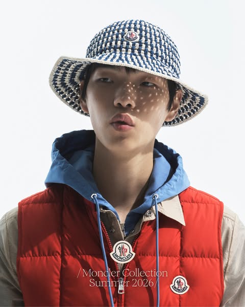 This ad showcases the Moncler Collection Summer 2026 and features a man wearing a blue and white bucket hat and a red pu