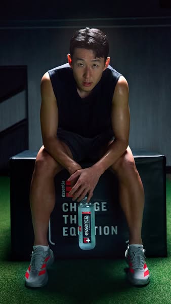 Image ad featuring Korean soccer player, Son Heung-Min, sitting on a gym box holding Essentia water.
