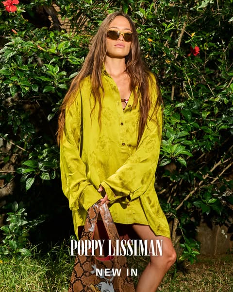 This image ad features a woman in a bright yellow outfit and sunglasses, holding a snakeskin-patterned tote bag with a c