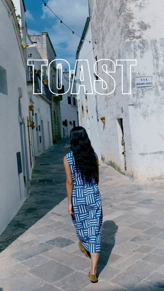 This ad for Toast features a woman walking down a European street in a blue-and-white patterned dress.