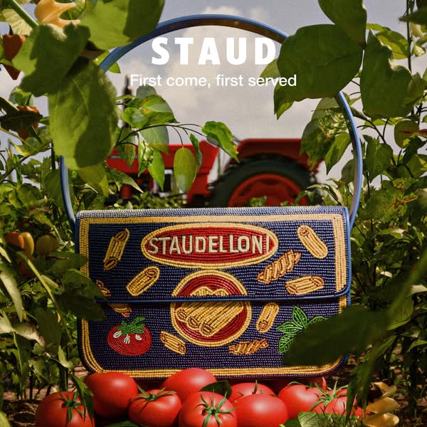 This image ad for Staud features a handbag with a trompe l'oeil design resembling a pasta box. It is set in a tomato