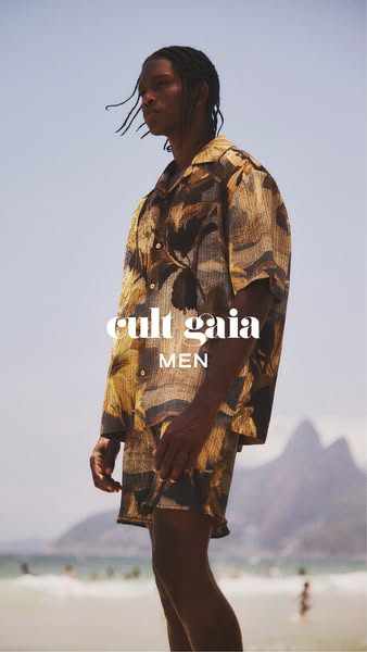 This ad features a man modeling a button up shirt and shorts from Cult Gaia's men's line on a beach.