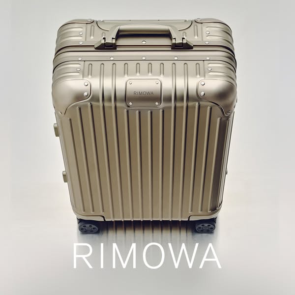 This ad features a high-angle shot of a Rimowa suitcase against a white background. The ad focuses on the suitcase's