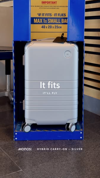 A close-up of the Monos Hybrid Carry-On - Silver suitcase inside of a luggage sizer to show that it fits the size requir