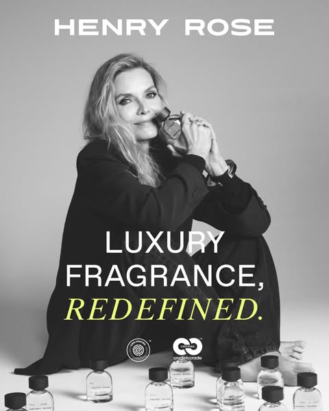 An image ad for Henry Rose fragrance featuring actress Michelle Pfeiffer sitting with legs crossed in a black blazer and