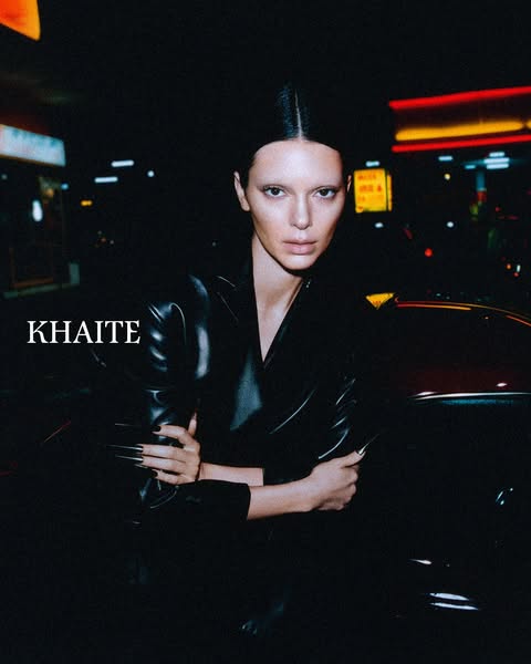 This image ad features a woman in a leather jacket, with the KHAITE brand name, in a dim, urban setting.