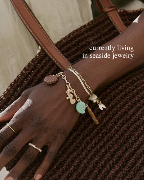 The ad features a close-up of a person's arm adorned with various pieces of gold jewelry. The focal point is a layer