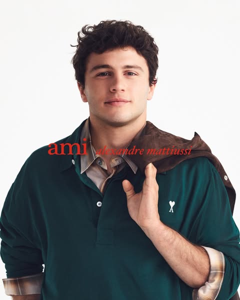 This image ad features a stylish man wearing a green long-sleeved polo shirt. The brand name 'ami' is displayed